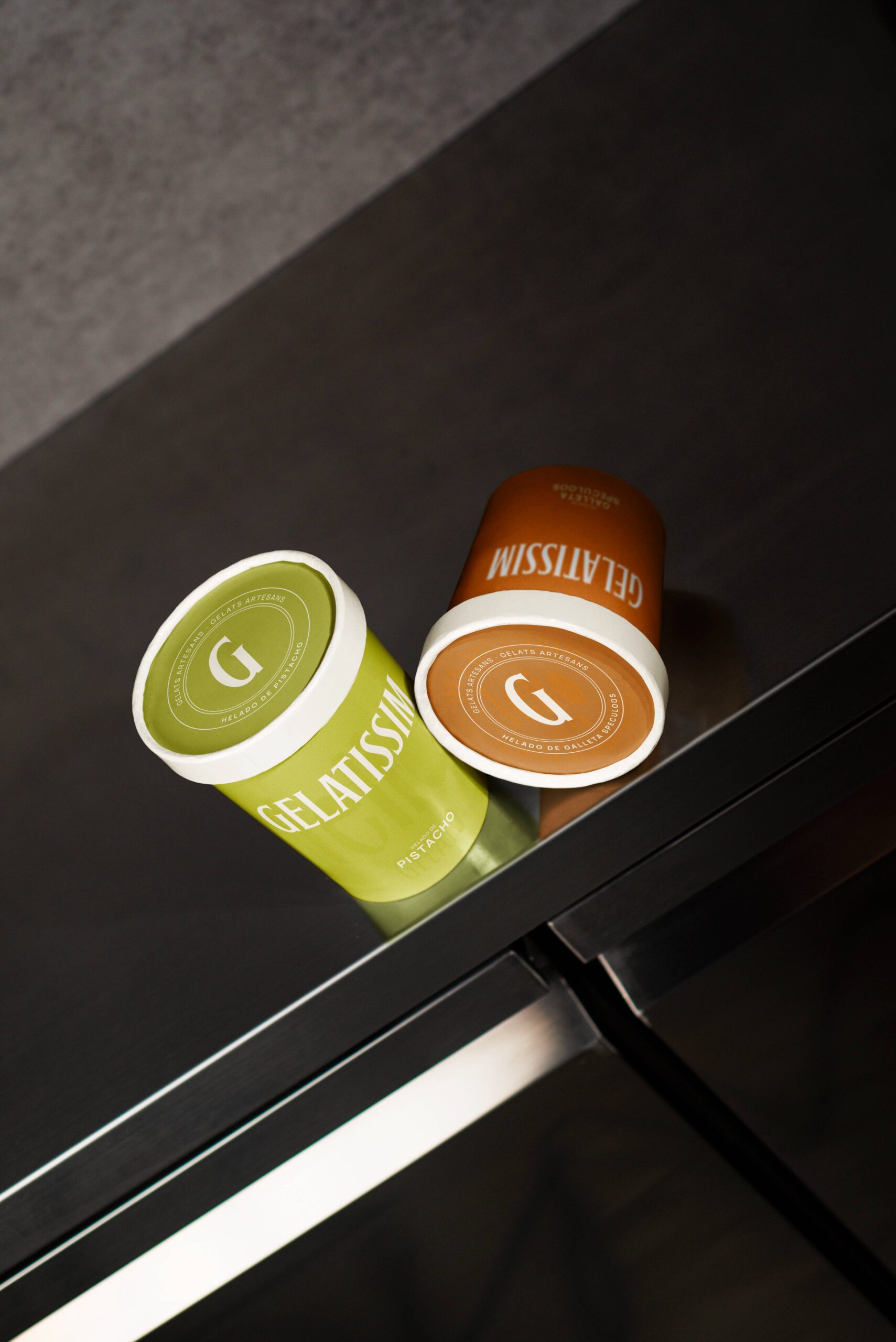 Tarrinas de helado Gelatissim de pistacho y galleta lotus sobre mostrador metálico.