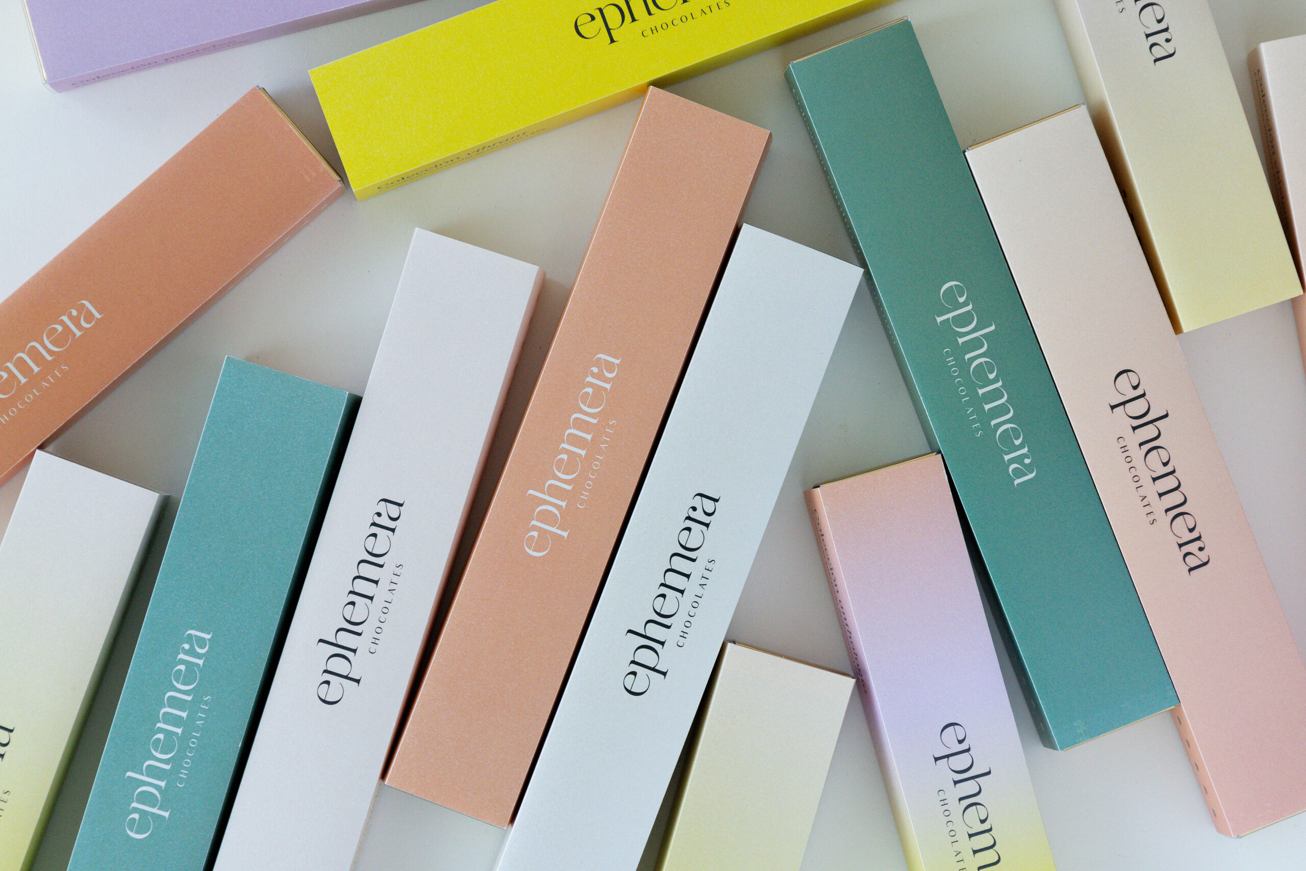 Colección de cajas alargadas de chocolates Ephemera en colores pastel con branding elegante y minimalista.