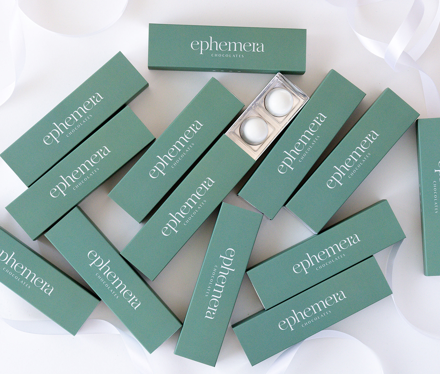 Composición de cajas de chocolates Ephemera en color verde salvia con diseño tipográfico minimalista.