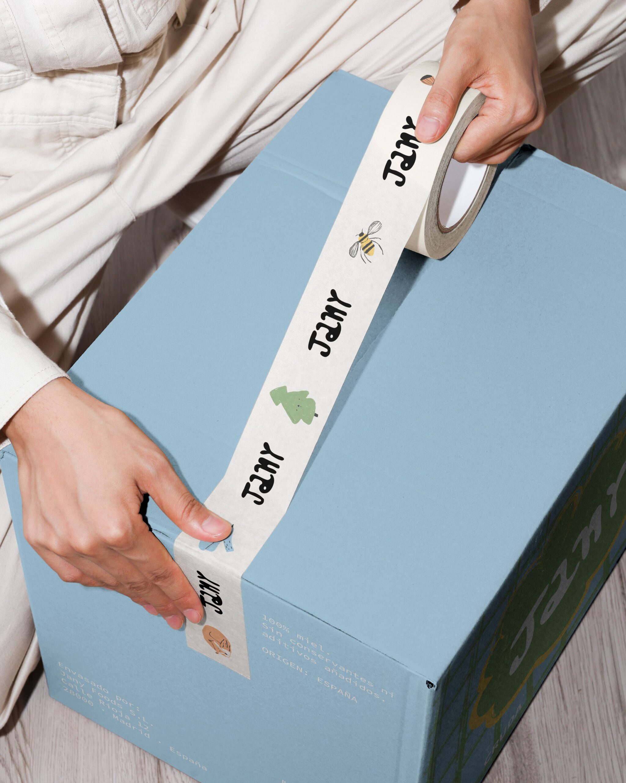 Caja de envío de Jany sellada con cinta adhesiva personalizada ilustrada, dentro del proyecto de branding y packaging para miel premium.