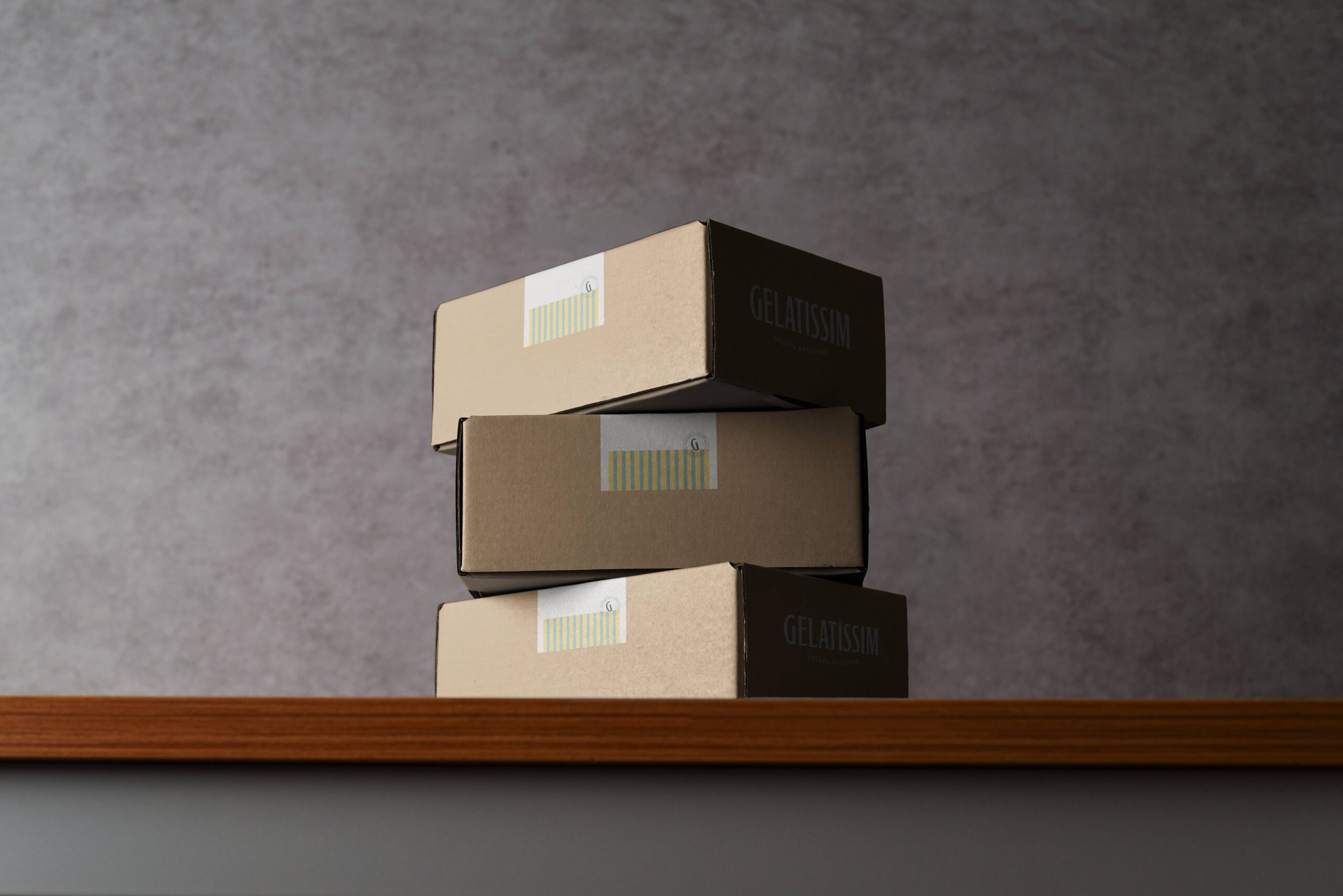 Cajas de packaging Gelatissim apiladas sobre estantería de madera.