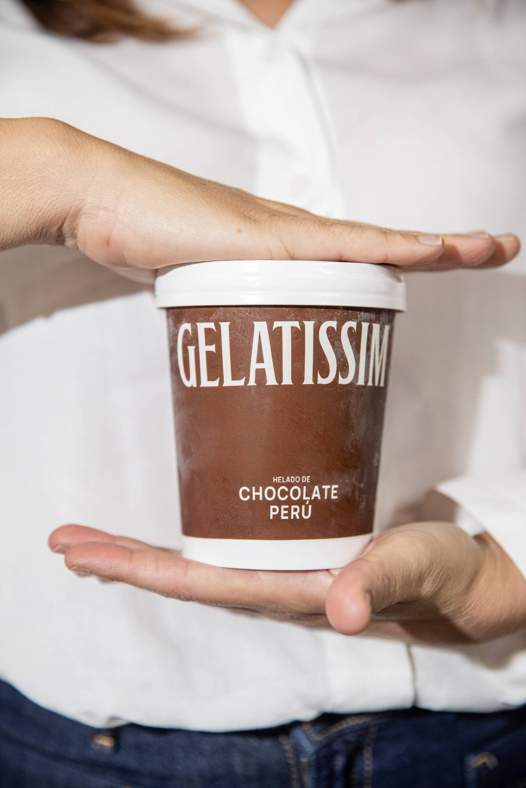 Persona sujetando una tarrina de helado de chocolate Perú de Gelatissim.
