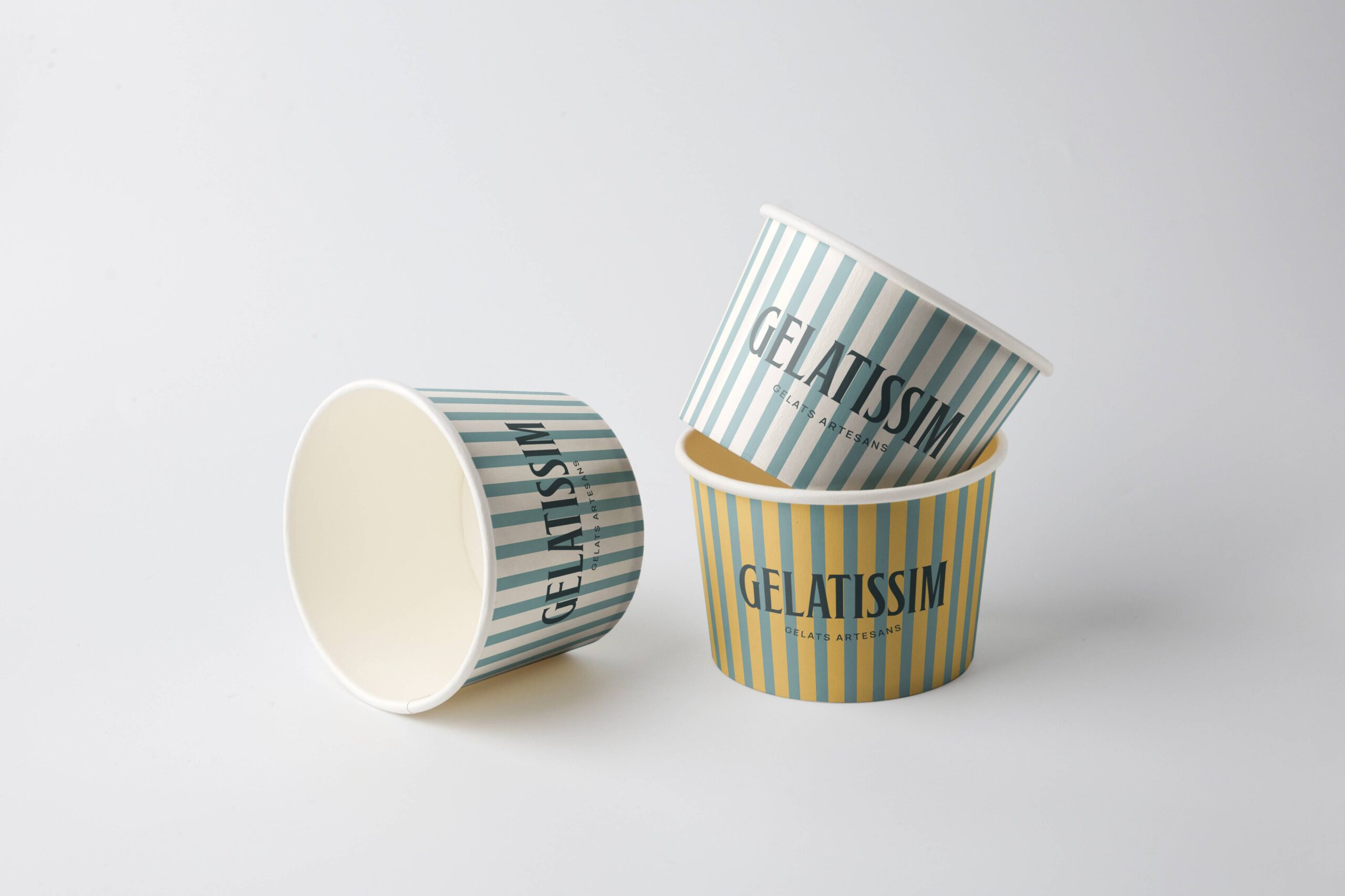 Vasos de helado Gelatissim con diseño de rayas en colores pastel sobre fondo neutro.