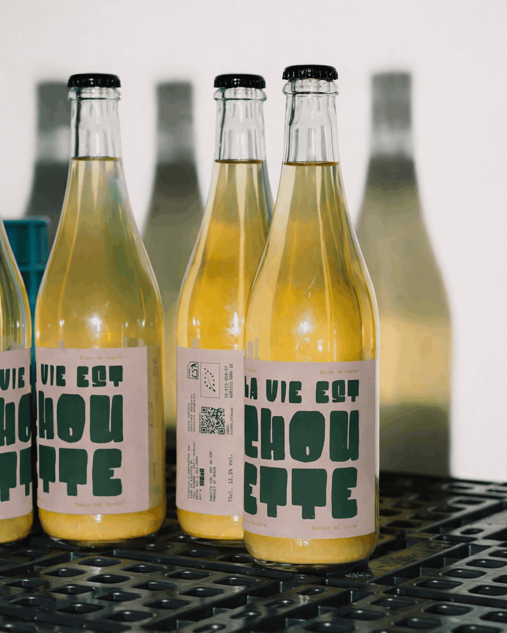 Botellas de vino La Vie Est Chouette en línea de producción con branding y packaging editorial.