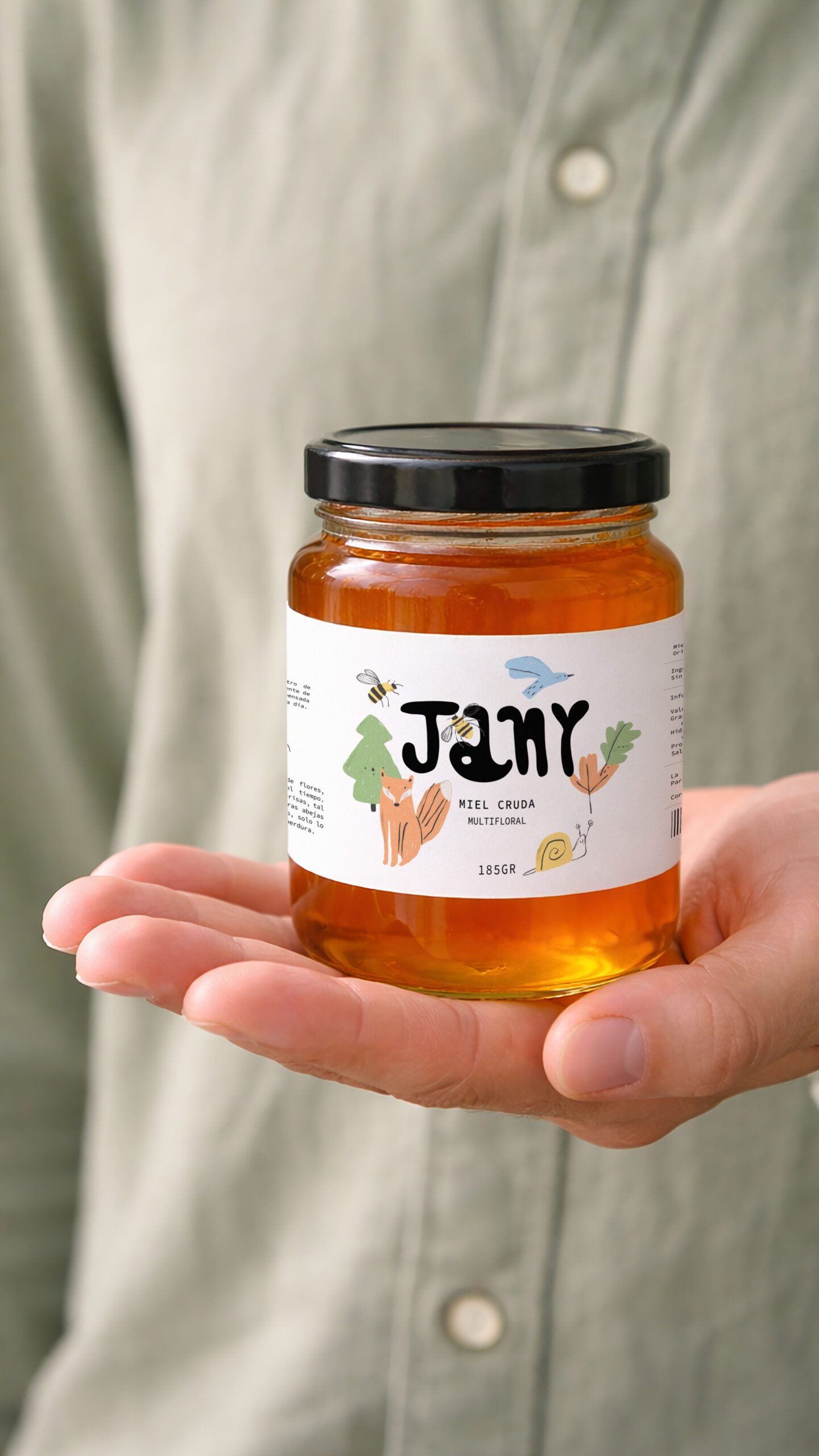Tarro de miel Jany sostenido en la mano mostrando el packaging artesanal y natural.