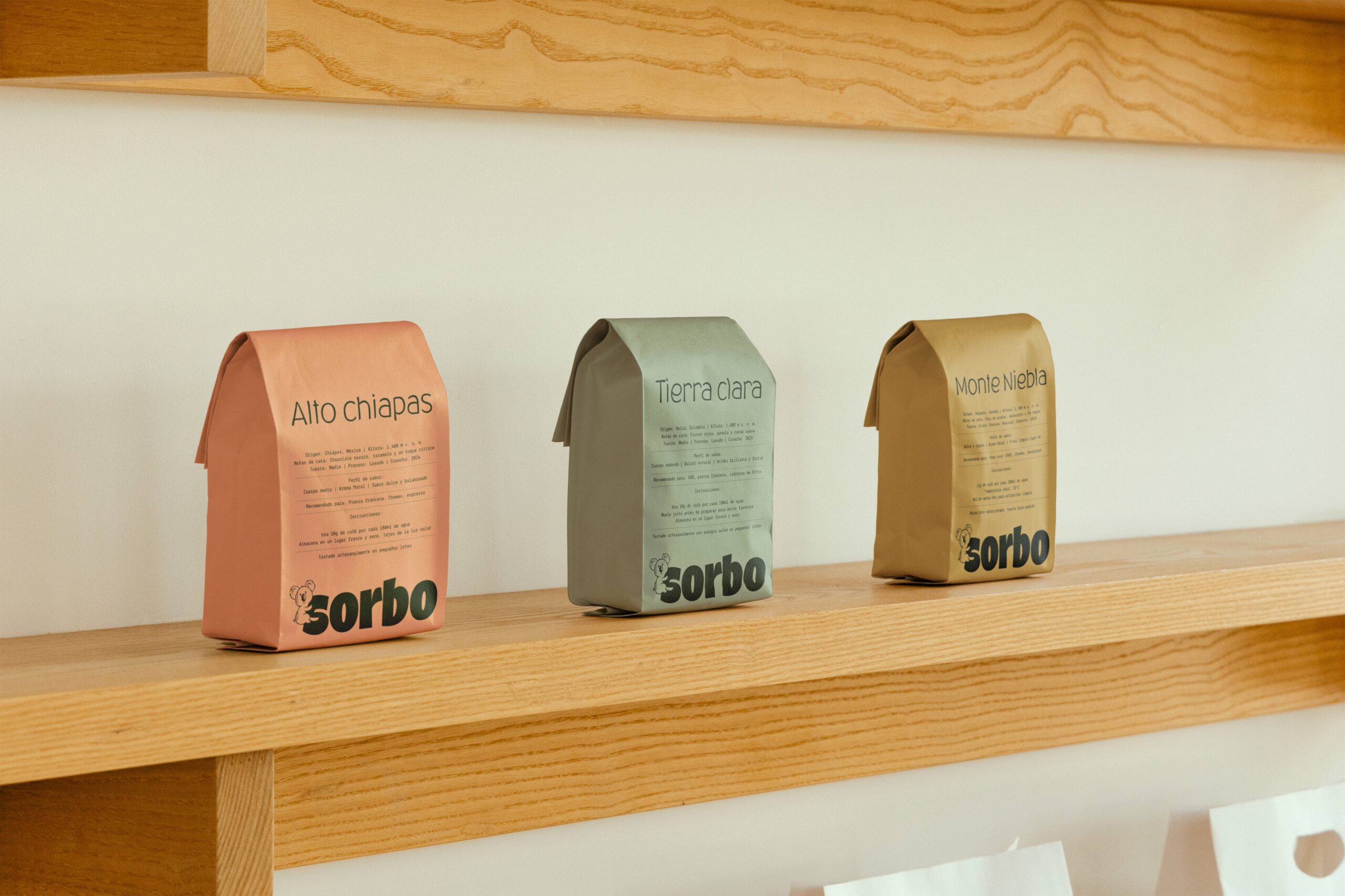 Tres bolsas de café de especialidad Sorbo (variedades Alto Chiapas, Tierra Clara y Monte Niebla) expuestas en un estante de madera clara.