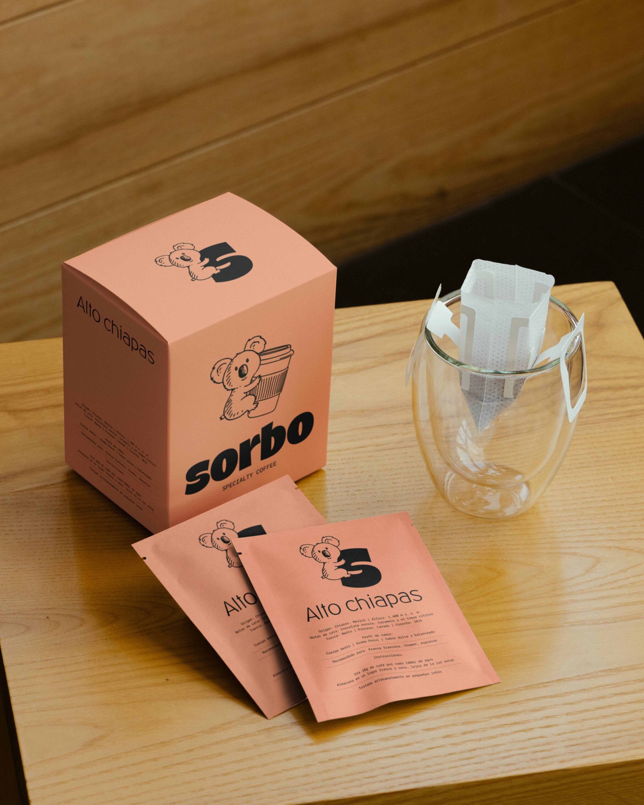 Set de café de goteo: caja de la variedad Alto Chiapas junto a sobres individuales y un filtro de café listo para infusionar en un vaso de cristal.