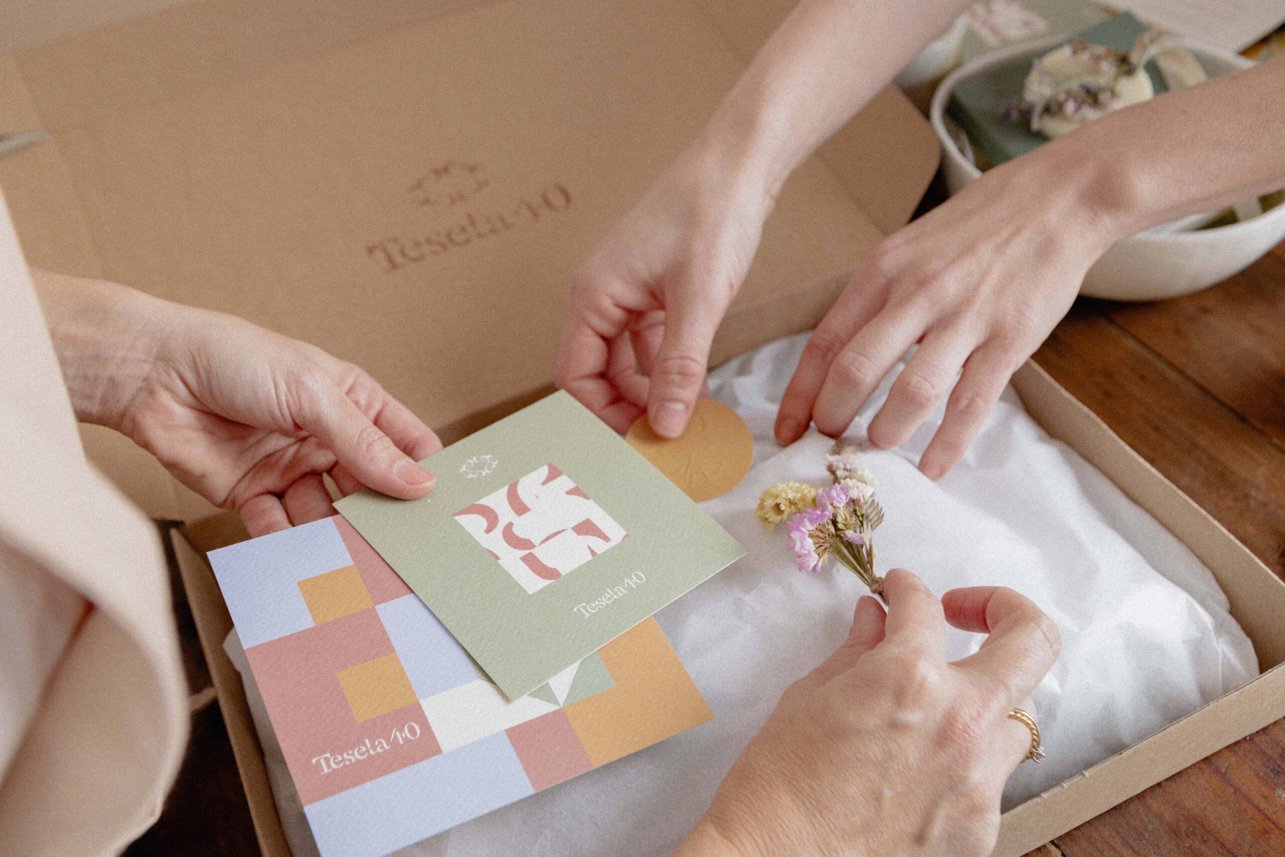 Branding aplicado: artesana trabajando con materiales naturales y elementos de identidad visual de marca sobre mesa de madera.