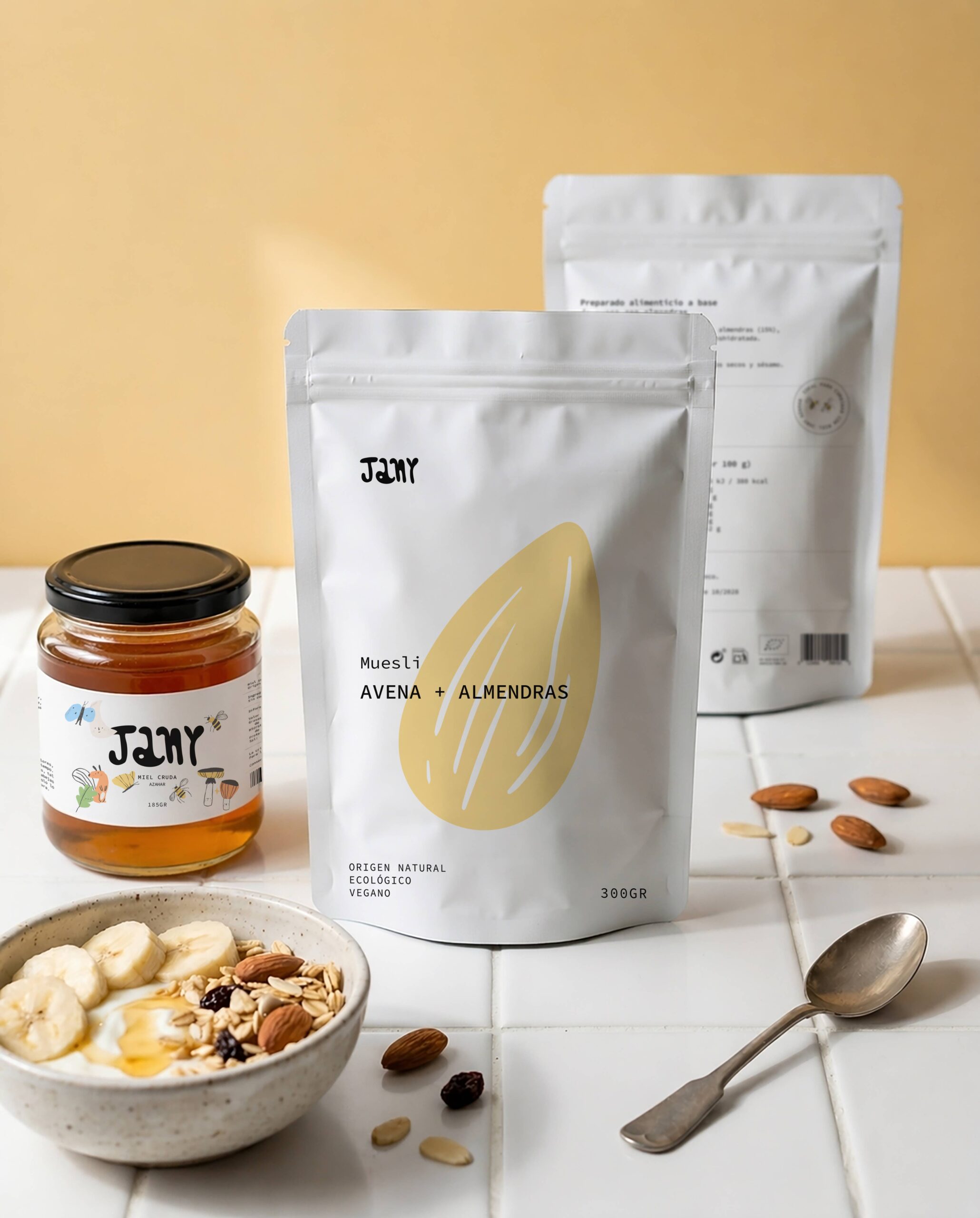 Bolsa de muesli Jany avena y almendras junto a miel Jany y bol de desayuno saludable.