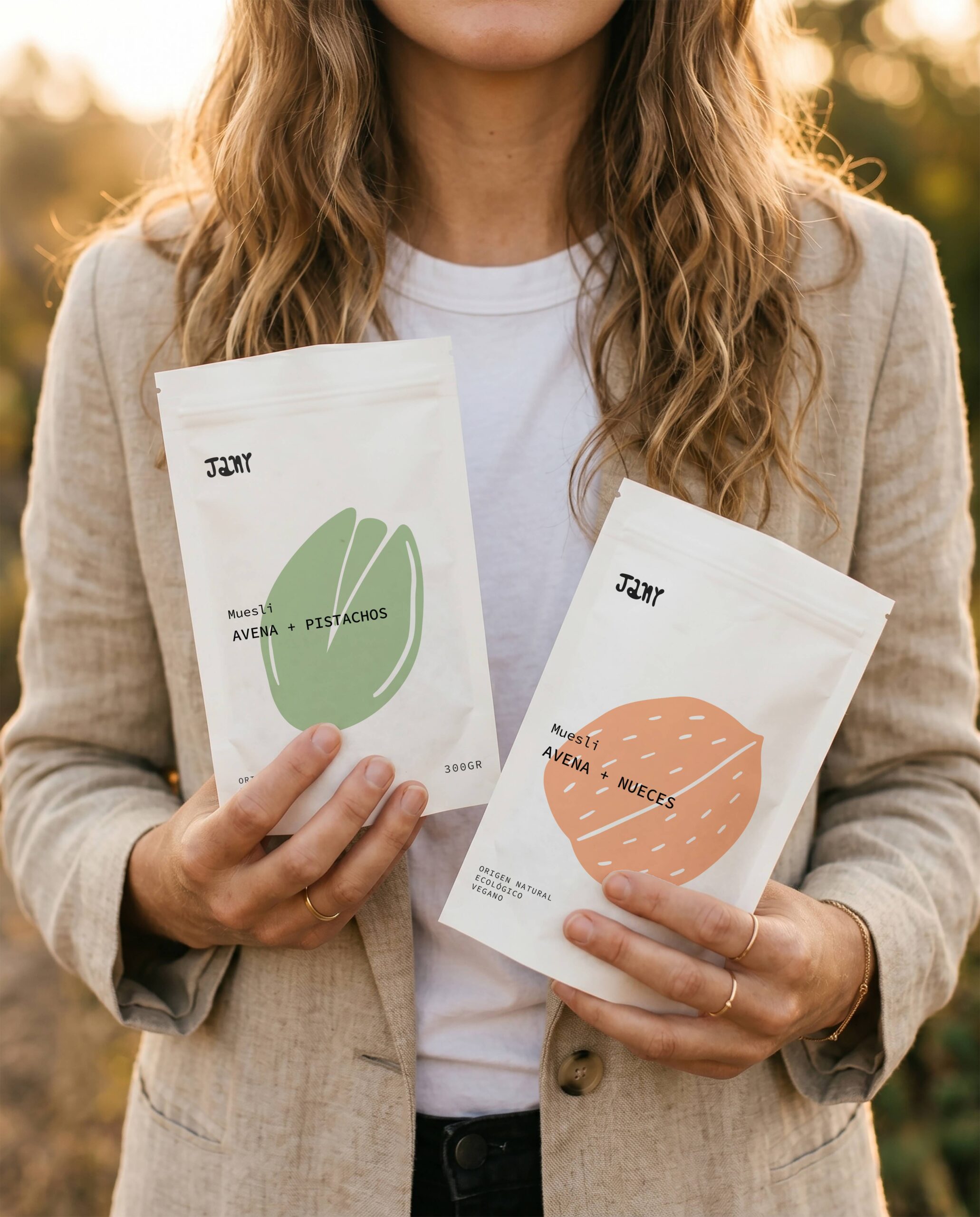 Persona sosteniendo dos bolsas de muesli Jany con diseño de packaging minimalista para avena y pistachos y avena y nueces.